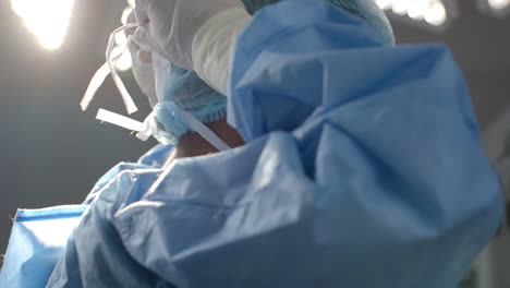 african american female surgeon wearing face mask in operating theatre, slow motion