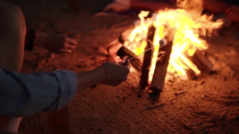 Nahaufnahme-Einer-Jungen-Hipster-Frau-Mit-Kopfhörern-Am-Hals,-Die-Marshmallow-Auf-Einem-Lagerfeuer-Braten