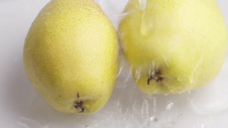 yellow pear on a blue dark background with drops of water rolling down the pear and flowing splashing with isolated background