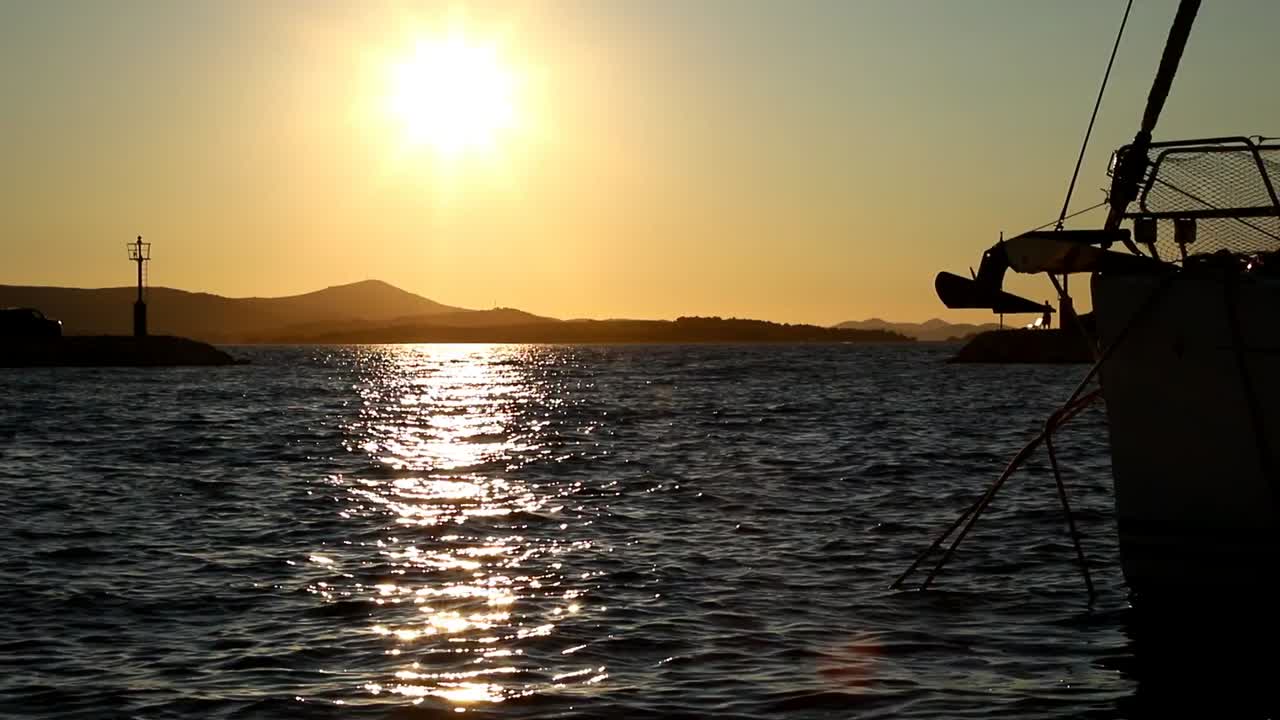 barcos y yates entran y salen del puerto deportivo al atardecer en biograd en croacia en cámara lenta
