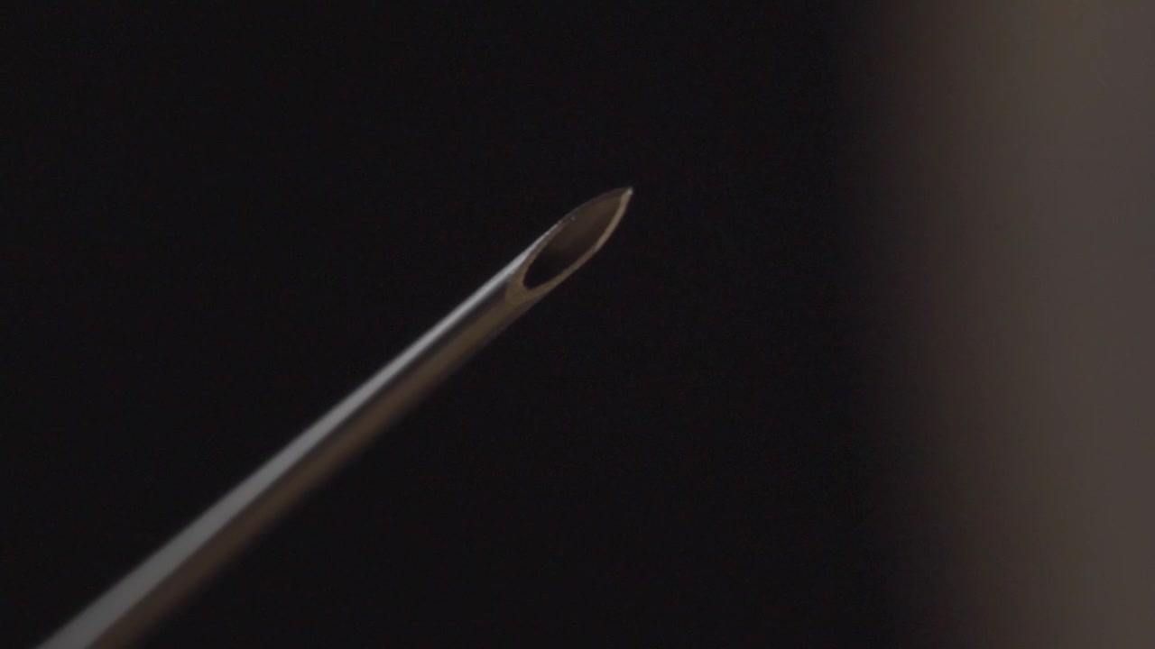 Macro closeup showing sterile hypodermic needle tip against dark background highlighting precision medical equipment for healthcare and clinical use