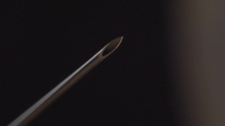 Macro closeup showing sterile hypodermic needle tip against dark background highlighting precision medical equipment for healthcare and clinical use