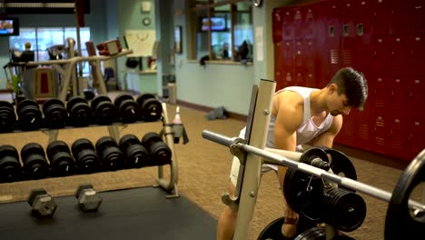 Teen-boy-bodybuilder-putting-a-large-weight-onto-a-barbell