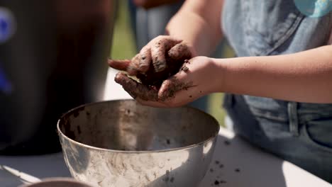 close up of person making a seed bomb above an iron bowl