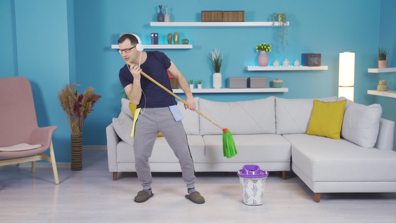 hombre acompañando la música con una escoba mientras limpia mientras escucha música.