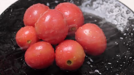 Pequeños-Tomates-En-Un-Plato-Oscuro-Que-Se-Desinfectan-Con-Agua