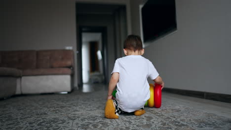 toddler boy runs up to a colorful pyramid. happy little kid playing at home cheerfully.
