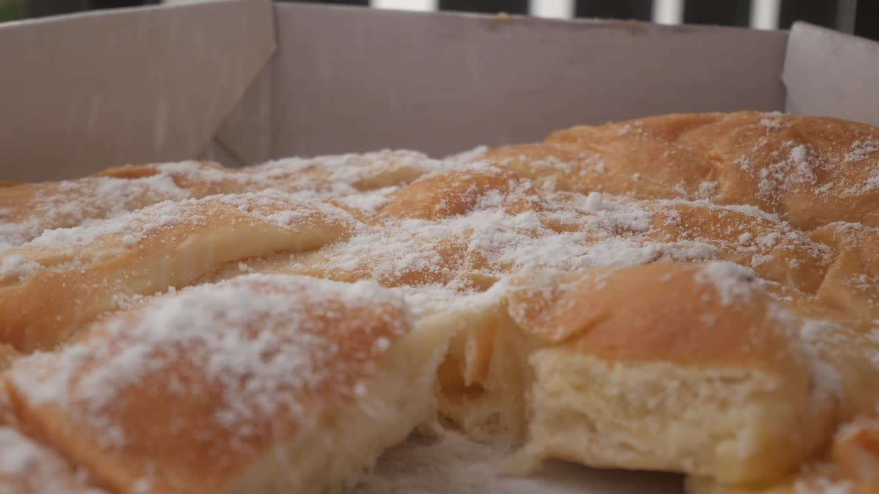 Ensaimada pastry from Menorca in a box, golden, fluffy, and dusted with sugar