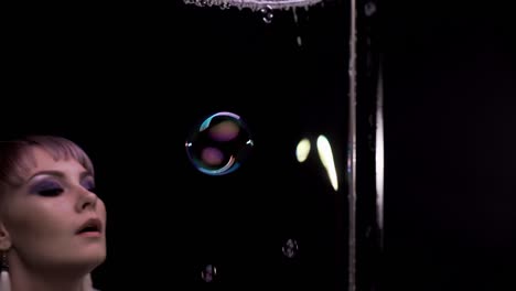 close-up: pretty girl does tricks with soap bubbles, she blows a lot of bubbles through the soap curtain