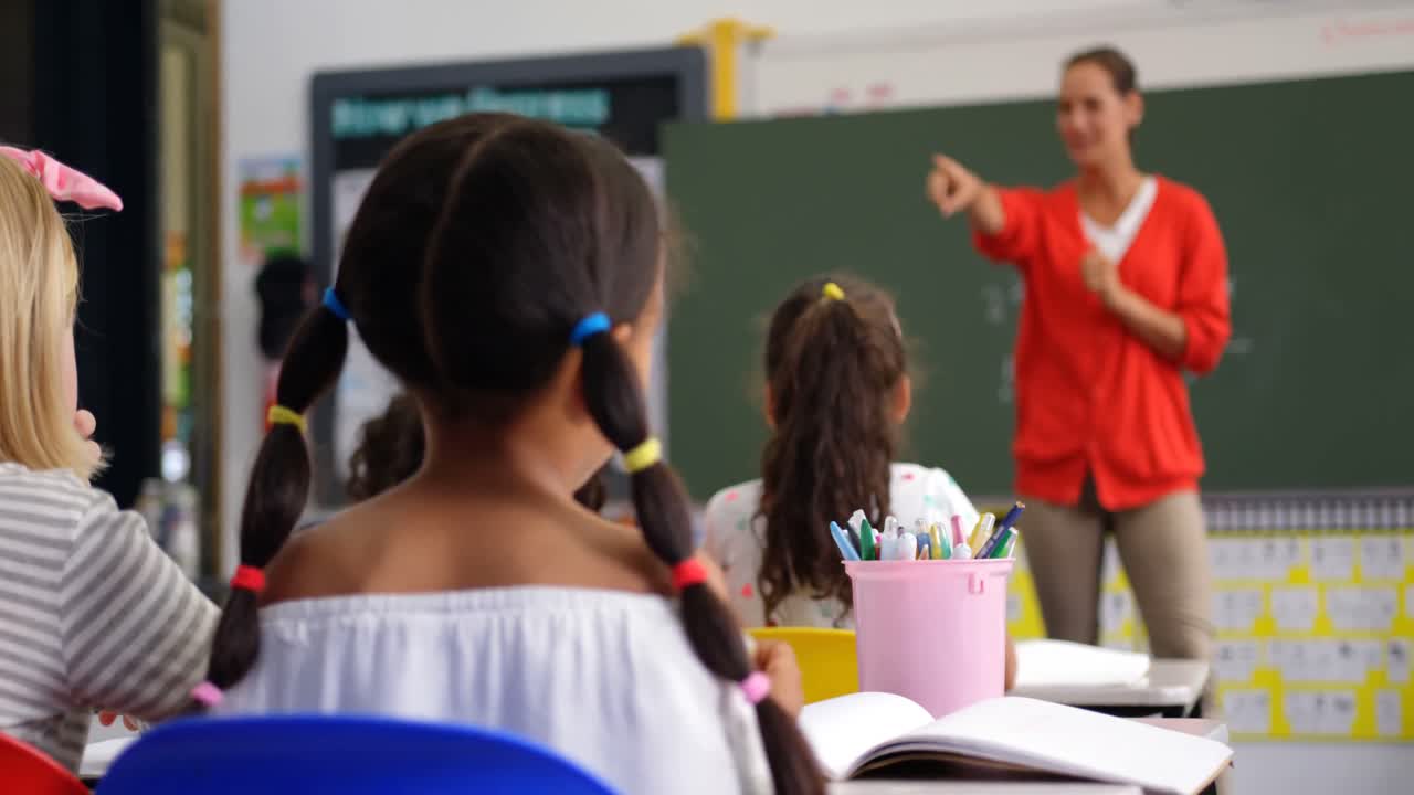 vista frontal de una maestra caucásica que enseña a los escolares en el aula 4k