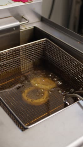 chef putting squid rings inside the professional fryer