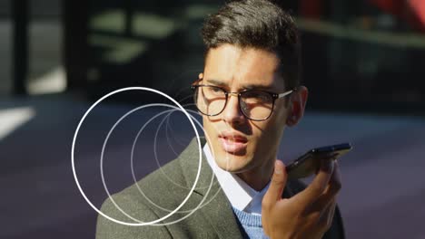 Animation-of-abstract-circular-shape-spinning-over-biracial-businessman-talking-on-smartphone