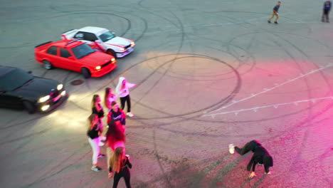 girl in a black hoodie dancing surrounded by her friends also moving. cars for drift around the people. top view.