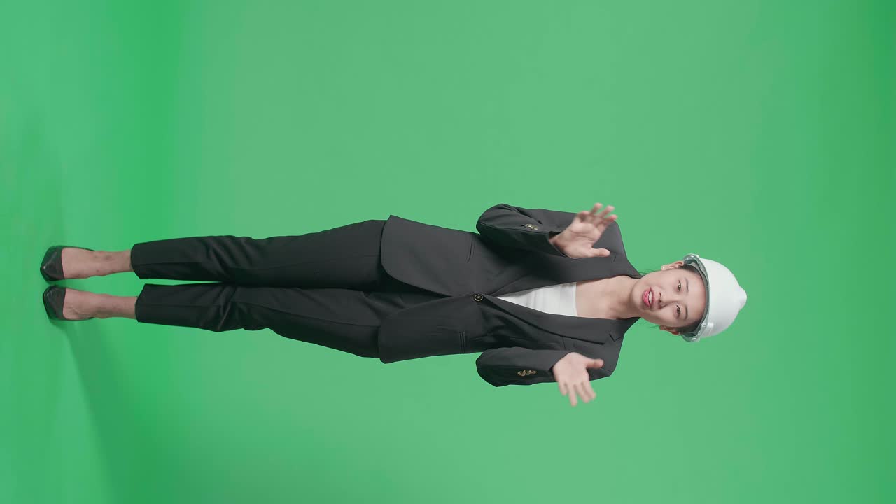 Full Body Of Smiling Asian Female Engineer Talking In The Green Screen Studio