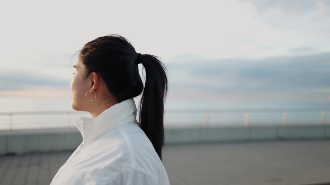 日の出の海を眺めて立っている若いアジア人女性