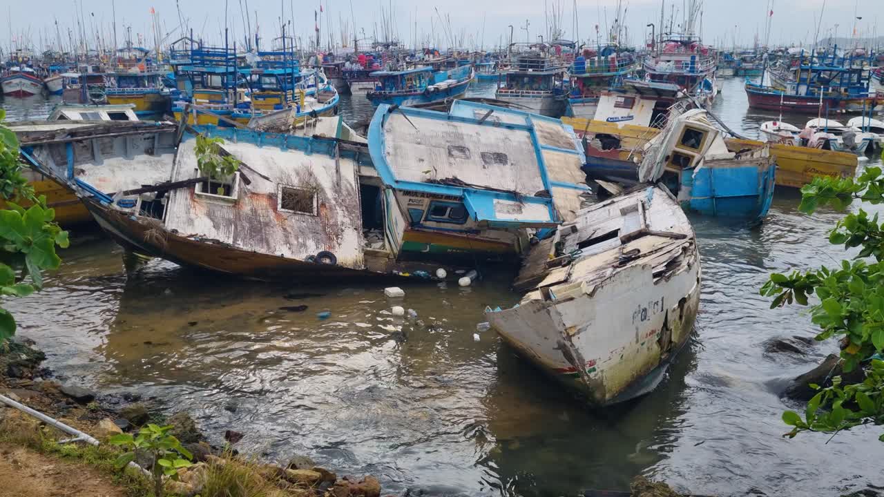 Captured at Dondra Port Fishing Market in southern Sri Lanka, a worn, damaged boat rests among tightly packed, colorful fishing vessels, showcasing lively coastal daily life