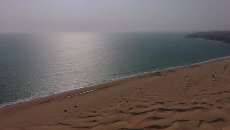 Vista-Aérea-Del-Mar-Arábigo-Con-Vista-Inclinada-Hacia-Abajo-De-Las-Dunas-De-Arena-Del-Desierto-A-Su-Lado-En-Baluchistán