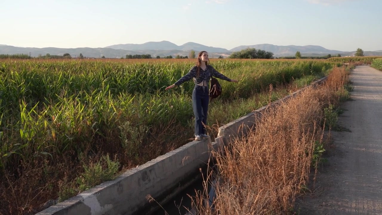 Una donna si gode una passeggiata panoramica lungo un bellissimo canale in un lussureggiante paesaggio agricolo.