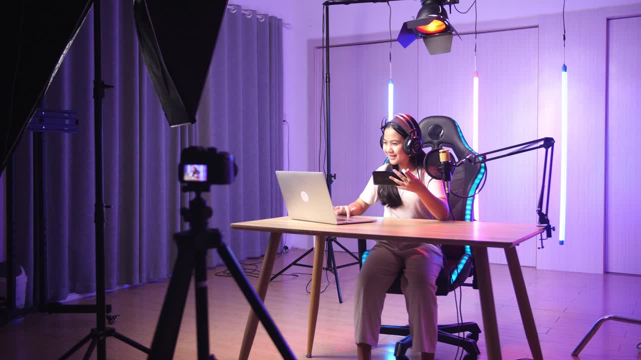 Asian Kid Girl Holding Mobile Phone And Read Comment In Laptop Computer Then Talking To Camera While Live Stream, Professional Light Equipment
