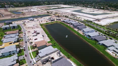 drone passes over waterway beside suburban homes with boat docks and green landscaping