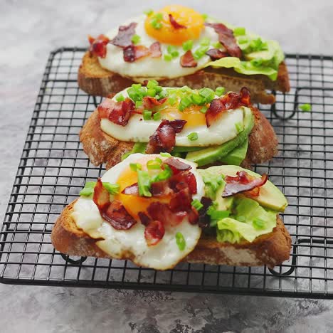 Tasty-delicious-homemade-toasts-with-fried-egg--bacon--avocado--lettuce-and-chive--Served-on-grill