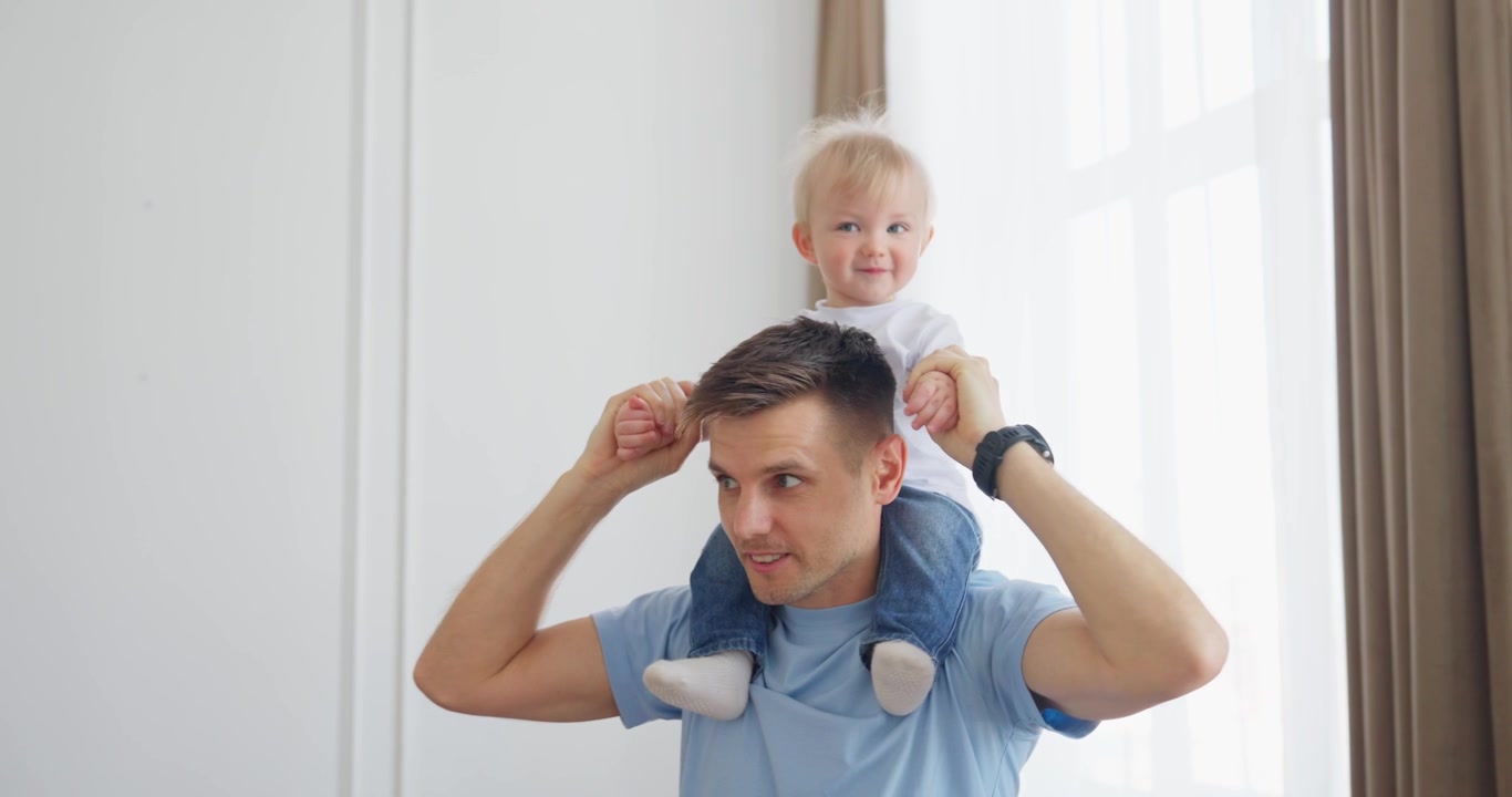 Happy Father Giving His Baby Son a Piggyback Ride at Home