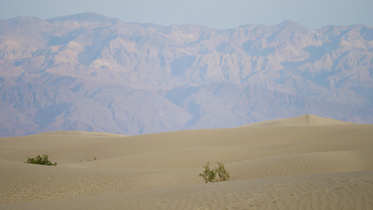 모래 언덕과 멀리 있는 산들로 이루어진 광활한 사막 풍경