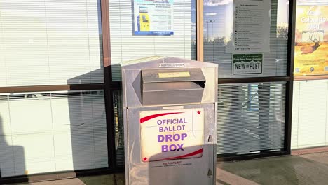 man drops mail-in ballot letter in slot at voting booth with offical ballot drop box sign for democratic government election in presidential race