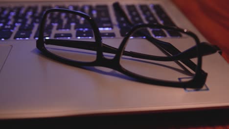 Slider-shot-moving-left-to-right-of-a-laptop-computer-sitting-on-a-kitchen-table-with-a-coffee-cup-in-the-foreground-and-eye-glasses-resting-next-to-the-keyboard