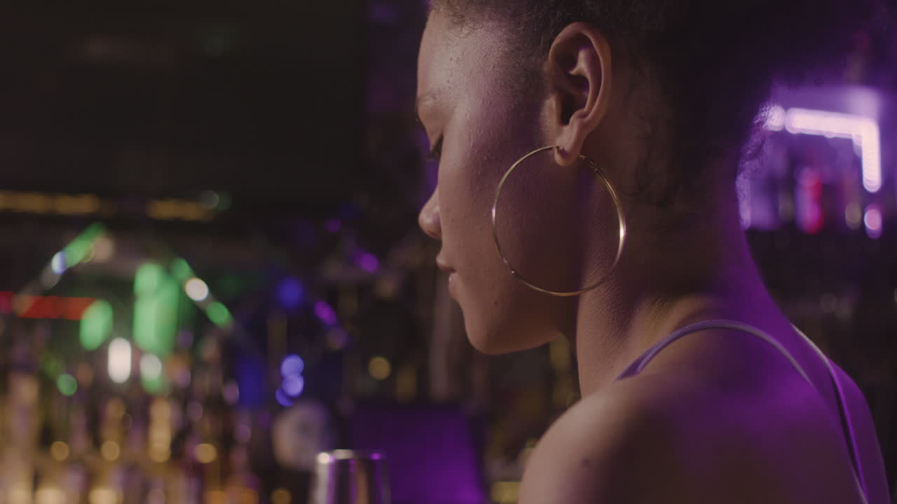 primo piano di una ragazza felice che beve e ride con qualcuno mentre è seduto al bancone del bar