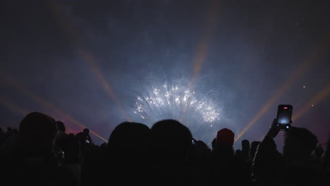 people filming colorful fireworks against a dark sky