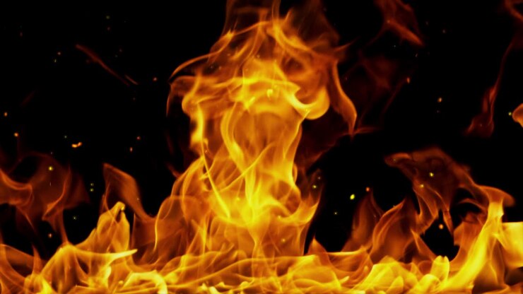 Fire with burning embers rising against a black background