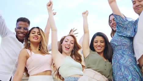 diverse group of friends celebrating together with arms raised
