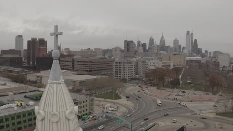 Drone-Closeup-of-Cross-and-Steeple-in-front-of-Philadelphia-City-Skyline-4K