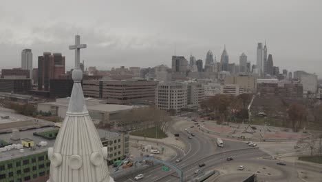 drone closeup of cross and steeple in front of philadelphia city skyline 4k