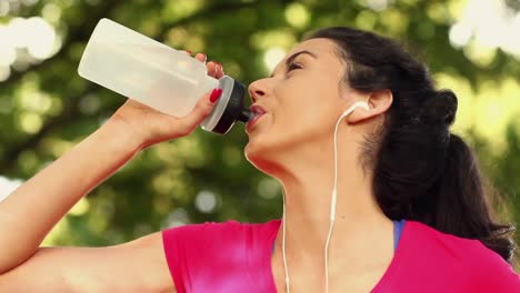 sporty brunette drinking water after her run