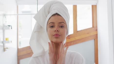 Portrait-of-woman-in-bathrobe-applying-face-cream