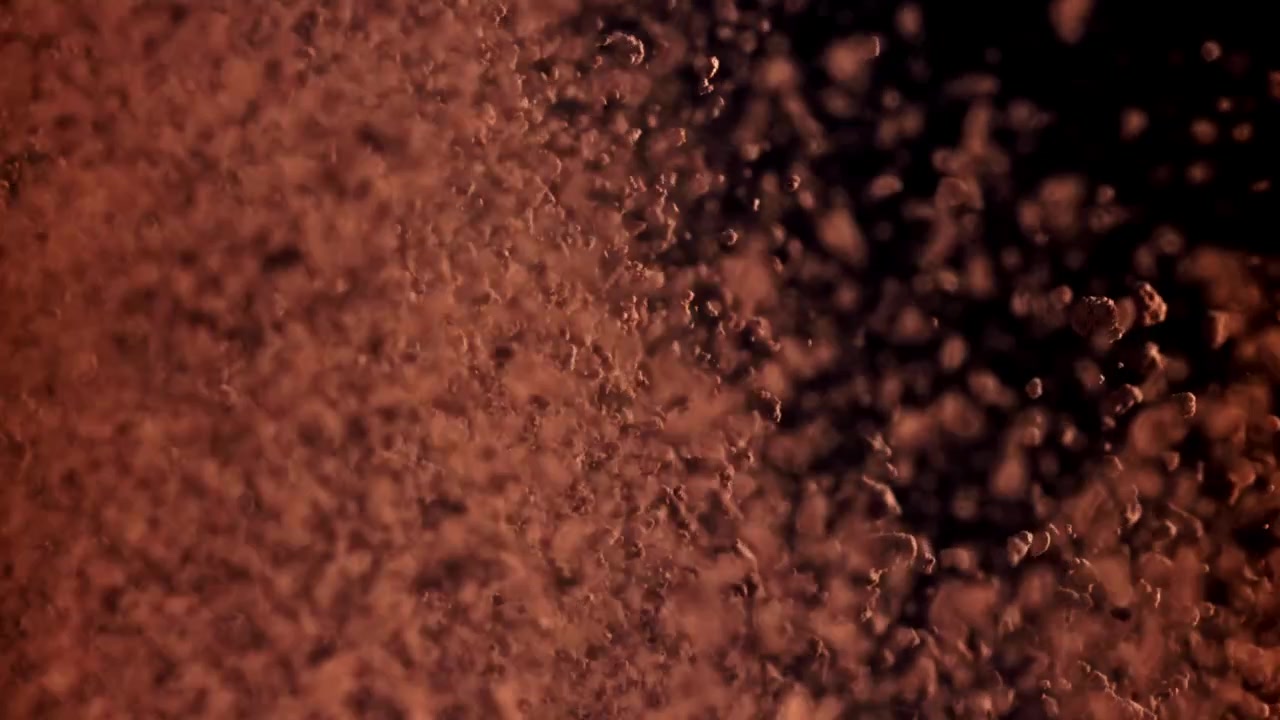 Dynamic Reddish Brown Powder Falling Against a Dark Background
