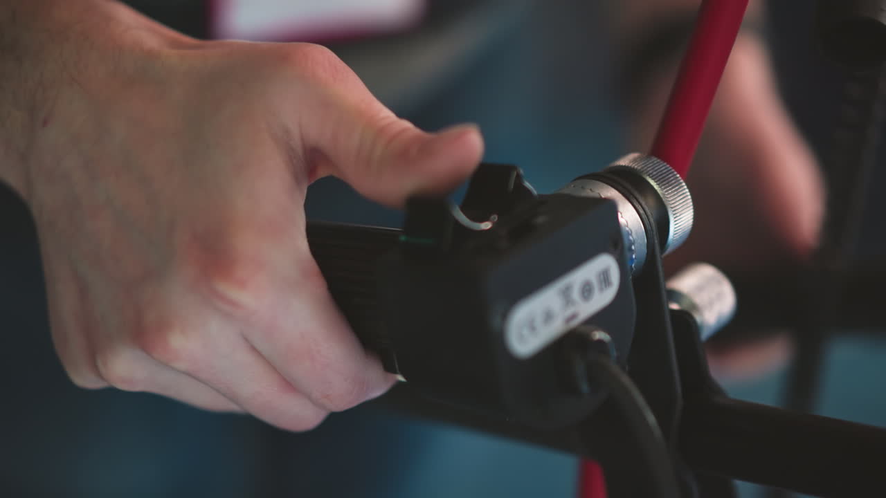 Close-up of hand adjusting camera focus zoom control on professional camera rig. Button labeled with W and T, highlighting the precision and control during filming in a broadcast studio