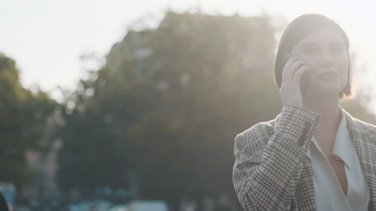 スタイリッシュな女性が外でビジネス電話をします