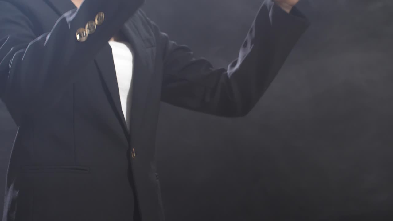 으로 보이는 지휘자의 손은 지이를 들고 검은 스튜디오에서 움직입니다.