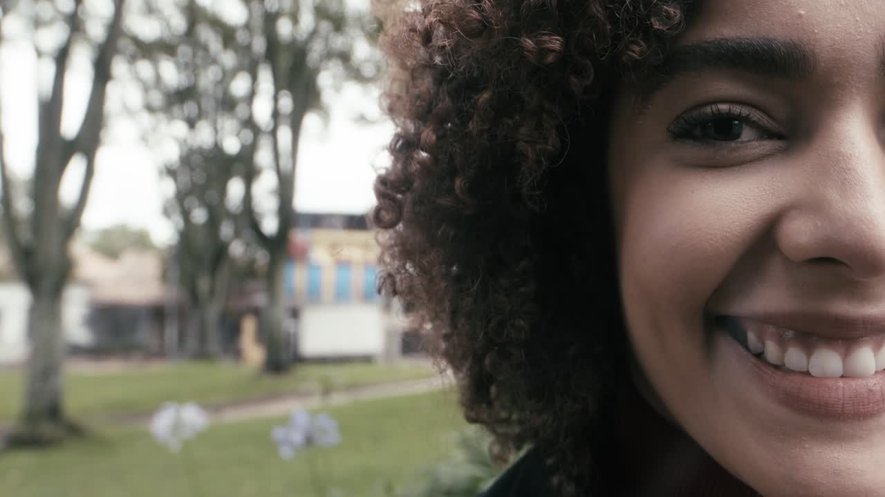 una mujer sonriente con el cabello rizado mira a su alrededor en la ciudad de bogotá, colombia