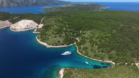 pakleni islands covered with green forest and yacht floating in the lagoon in croatia. - aerial shot