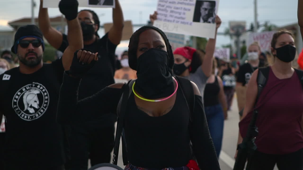 Mixed ethnicity crowd protesting with raised fist at Black Lives Matter protest, medium shot