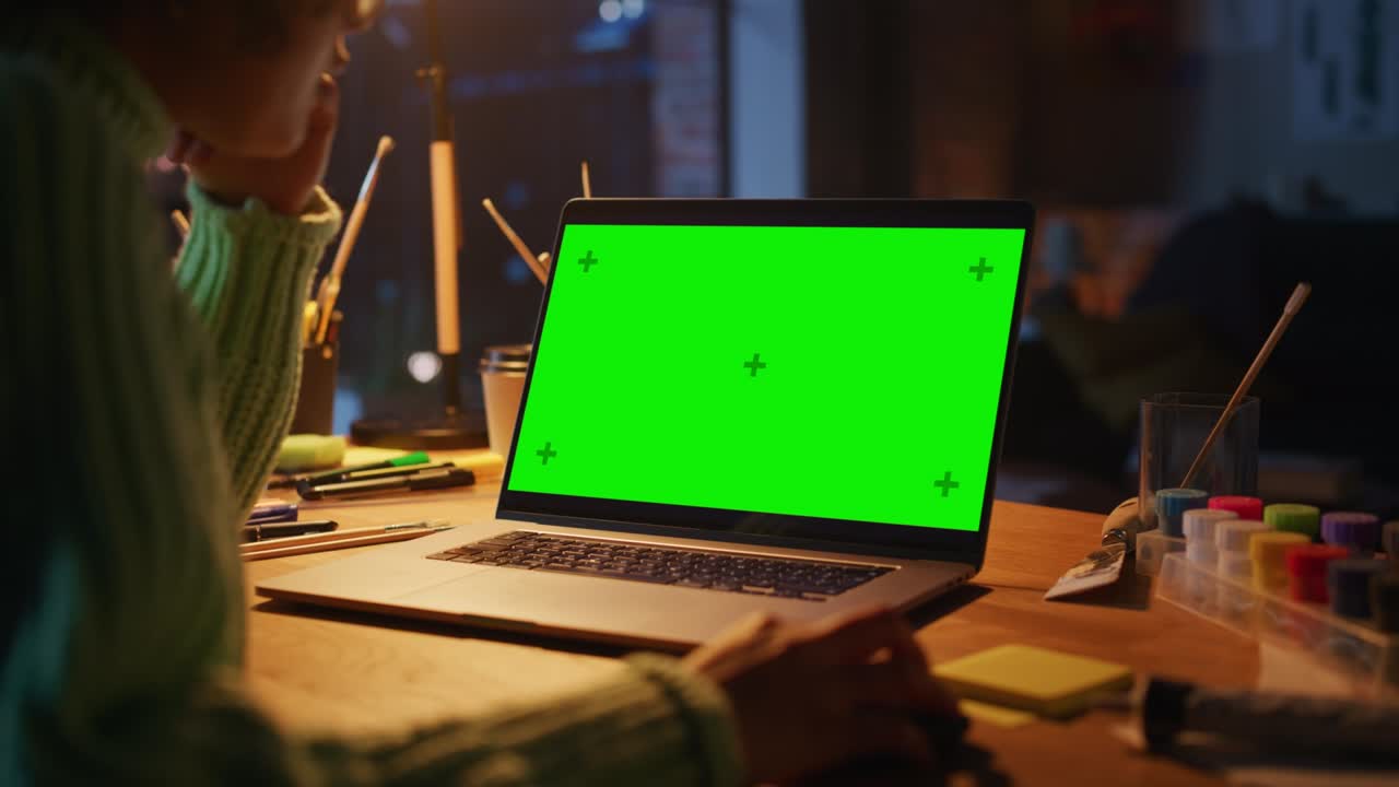 Close Up View of Brasilian Female Designer Working at Laptop with Green Screen. Woman Using Computer Mouse while Creating New Project. Freelance and Millennial People Concept. Over the Shoulder