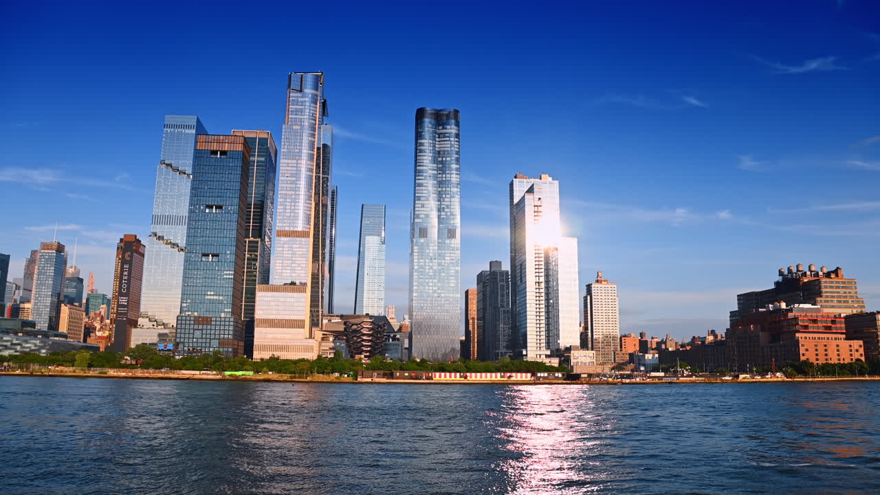 Il sole splendente si riflette sulle facciate dei moderni grattacieli. Vista dal basso degli edifici sul lungofiume di New York, USA, dal fiume