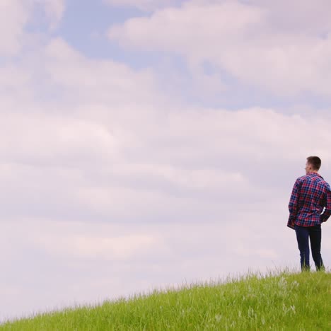 two young men stand on top of a green mountain