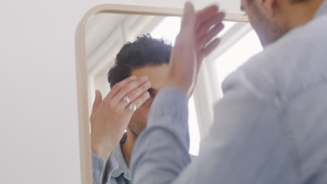 Dark-haired-man-checking-his-hairstyle-in-the-mirror.