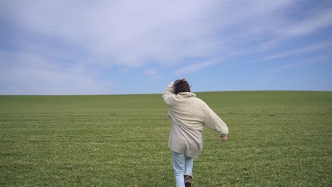 a young beautiful brunette girl walks through a green meadow. she invites us to follow her.