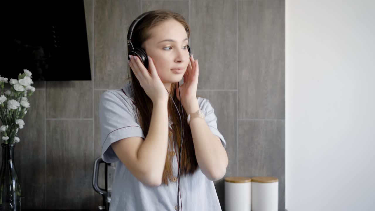 Lovely teenage girl is listening music in headphones indoor